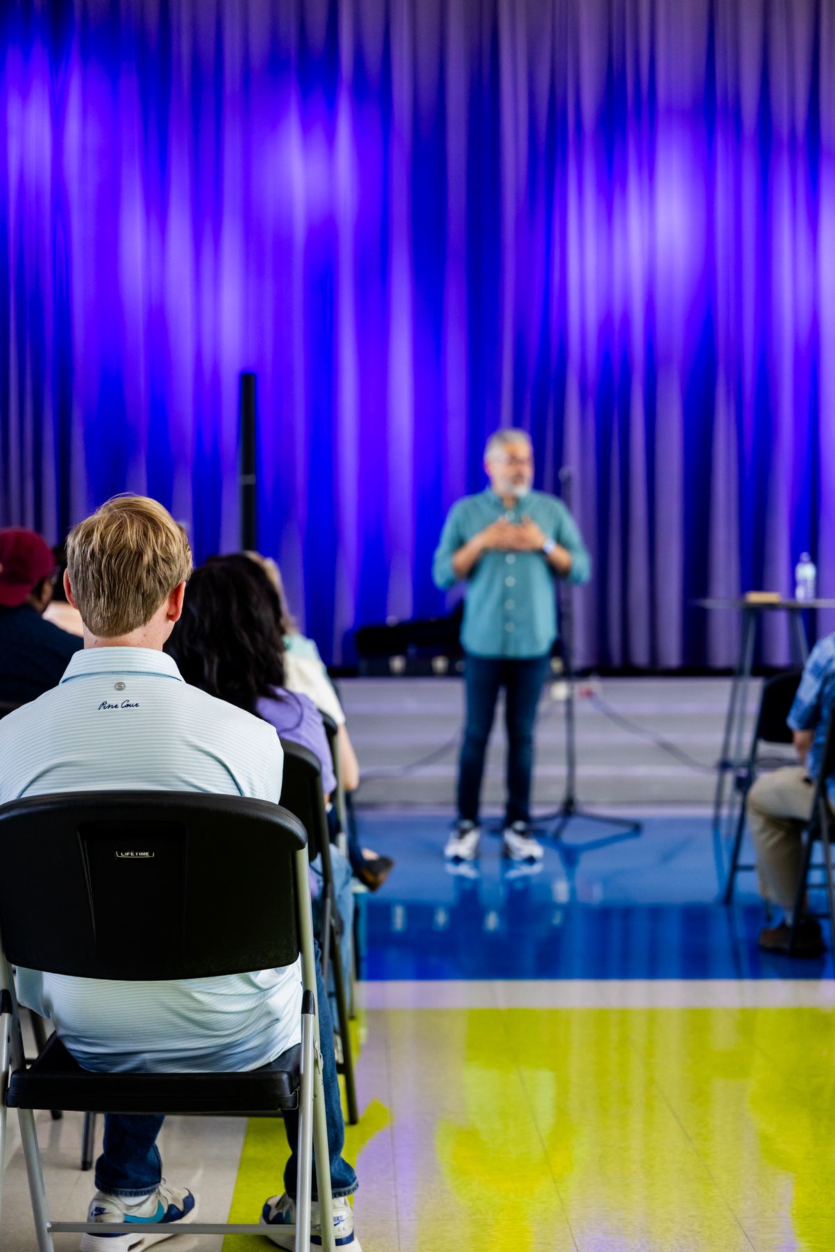 Audience watching a speaker on a small indoor event stage