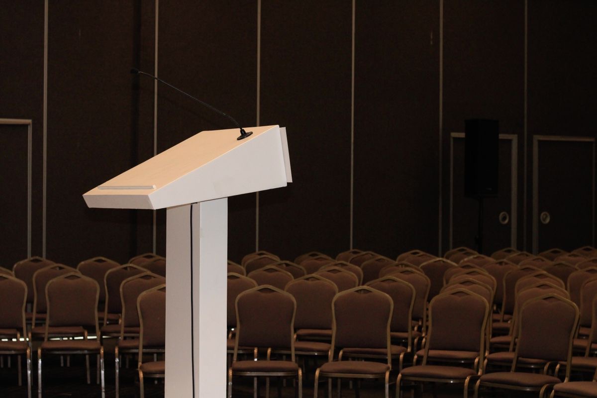 White podium in front of rows of chairs in a conference room